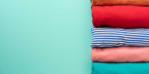  A close-up of rolled colorful clothes on green background.